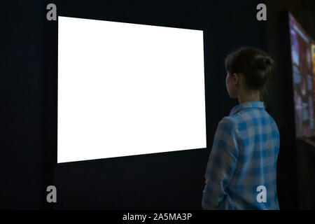 Woman looking at white empty large wall display - mockup image Stock Photo