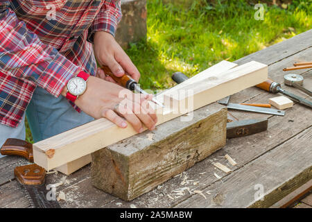 a young man working with wood outdoors during a summer day Stock Photo