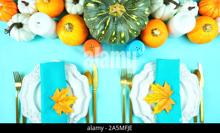 Happy Thanksgiving setting modern elegant blue orange and white themed table with pumpkins centerpiece overhead flat lay. Stock Photo