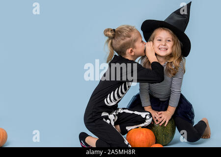 Brother whispers jokes in sister's ear. Halloween secrets Stock Photo