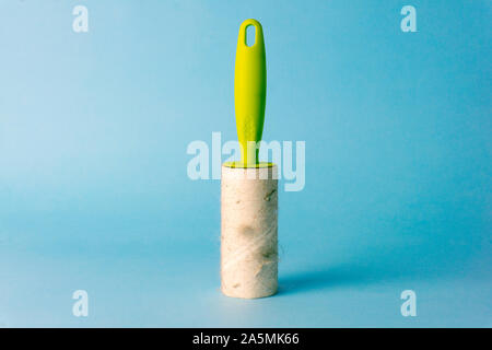 Lint roller (cleaning clothes roller) with trash on a blue background. Minimal concept. Stock Photo