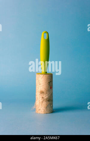 Lint roller (cleaning clothes roller) with trash on a blue background. Minimal concept. Stock Photo