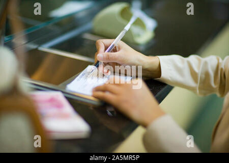 Women's hands writing in a check book. Stock Photo