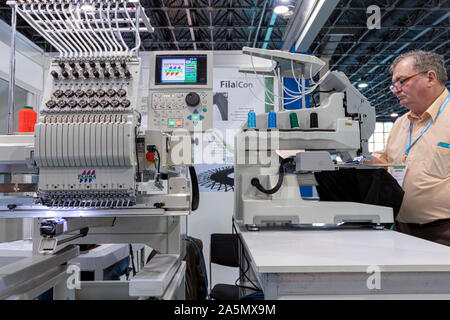 BUDAPEST/HUNGARY - OCTOBER 18, 2019: Technology trade show. A man operates an intelligent industrial embroidery machine. Stock Photo
