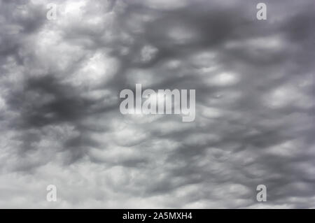 A completely overcast sky with a continuous layer of gray and dark clouds, so large and thick that they hide the sunlight. Stock Photo