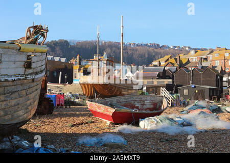 Hastings. In the foreground part of a wooden boat in disrepair. Picture centre an open boat and behind a twin masted wooden clinker built fishing boat Stock Photo