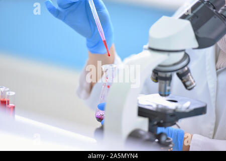 Young female scientist looking through a microscope in a laboratory doing research, microbiological analysis, medicine. Stock Photo