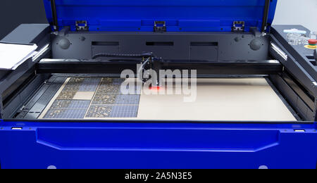 Laser engraving machine cutting leaves on invitation card Stock Photo