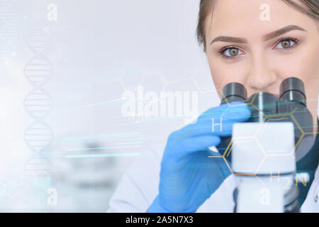 Young female male scientist looking through a microscope in a laboratory doing research, microbiological analysis, medicine. Female scientist looking Stock Photo