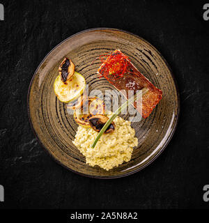 Grilled salmon served with zucchini, champignon and basil risotto Stock Photo