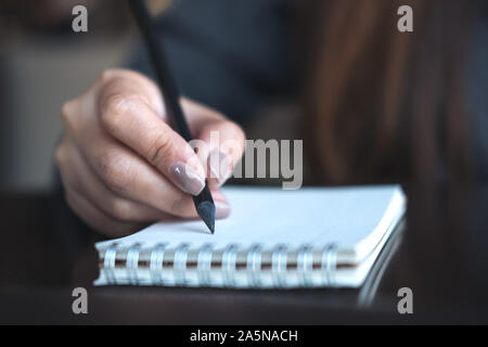 Closeup image of a woman's hands writing on notebook on the table Stock Photo