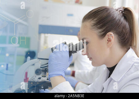 Young female scientist looking through a microscope in a laboratory doing research, microbiological analysis, medicine. Stock Photo
