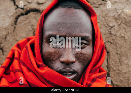 JUN 24, 2011 Serengeti, Tanzania - Portrait of African Masai or Maasai tribe man in red cloth eyes staring at camera. Clearly face detail wrinkle and Stock Photo