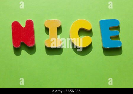 the word NICE in wooden letters lies on a green surface Stock Photo
