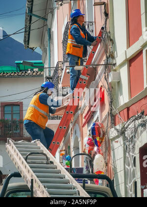 Quito, ECUADOR - 02 October 2019: Electricians are climbing on electric poles to install and repair power lines Stock Photo