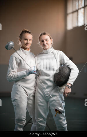 A portrait of two young women fencers holding swords Stock Photo