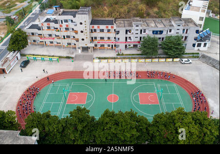 (191022) -- LUOTIAN, Oct. 22, 2019 (Xinhua) -- Aerial photo shows students exercising with teachers at Hope primary school in Luotian County, central China's Hubei Province, Oct. 11, 2019. Fang Rong, 29, is the headmaster of Hope primary school of Luotian County, her alma mater. Born in a poverty-stricken region, Fang Rong was a left-behind girl. Thanks to the Hope Project and people's aids, she succeeded in graduating from a secondary normal school. To help more children and repay people's kindness, she decided to be a teacher at her alma mater. In spite of the austere way of life, Fang Stock Photo