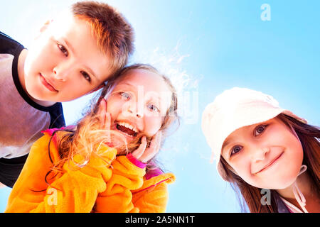 Group of three happy, surprised children looking down at the viewer. Stock Photo