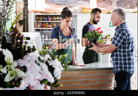 Customer Buying Plant And Sales Clerk Scanning Barcode Stock Photo