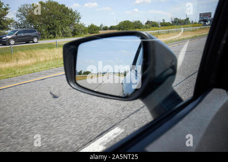 looking in car wing side-view mirror driving along the interstate indiana USA Stock Photo