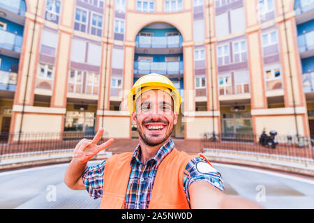Happy man architect at a building site takes a selfie looking at the camera Stock Photo