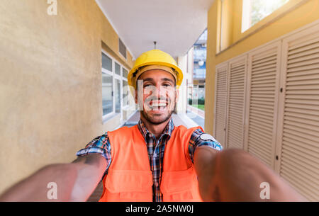 Happy man architect at a building site takes a selfie looking at the camera Stock Photo