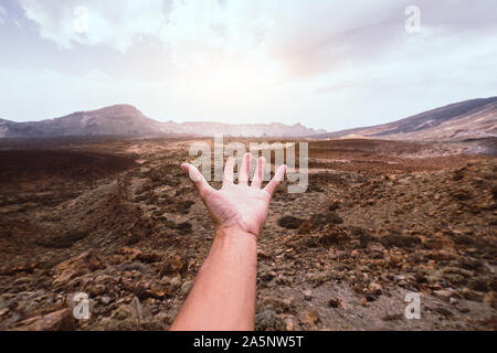 Hand of a man reaching out the beatiful mountain landscape at sunse Stock Photo