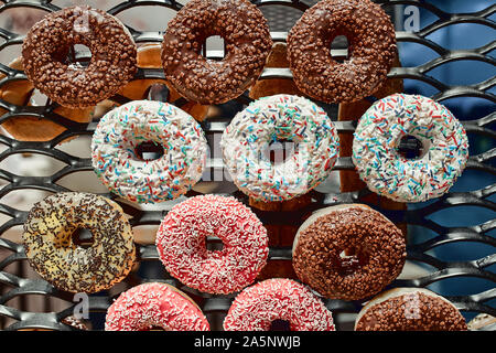 Multi-colored glazed donuts on a wire rack. Fast Food Concept, Delicious Dessert. Stock Photo