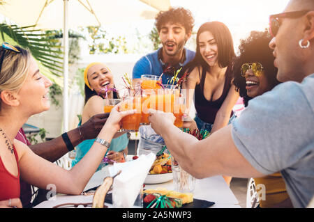 Young multiracial friends toasting beer at barbecue garden party - Young cheerful people cheering with cocktails on summer time Stock Photo