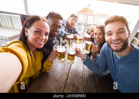 Happy multiracial group of friends taking a selfie drinking a beers at party Stock Photo