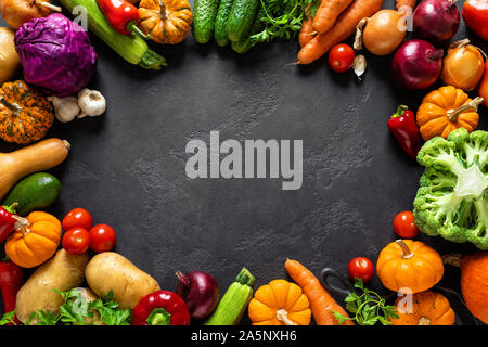 Culinary background with fresh raw vegetables on a black kitchen table, healthy vegetarian food concept, flat lay composition, top view Stock Photo