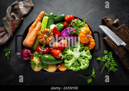 Culinary background with fresh raw vegetables on a black kitchen table, healthy vegetarian food concept, flat lay composition, top view Stock Photo