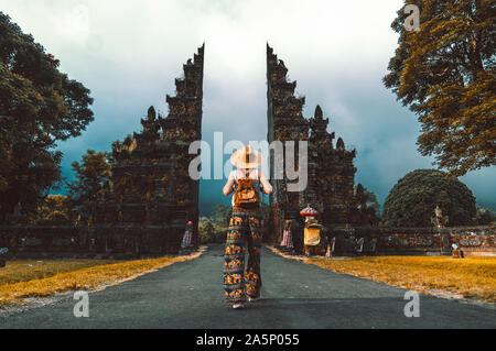Tourist woman with backpack at vacation walking through the Hindu temple in Bali in Indonesia Stock Photo