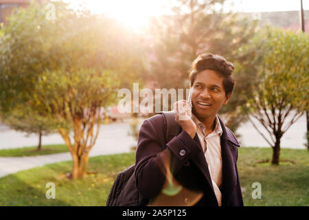 Attractive Indian man in a business suit and coat with a backpack walking Stock Photo
