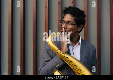 Funny handsome Indian man with a golden color inflatable tube Stock Photo