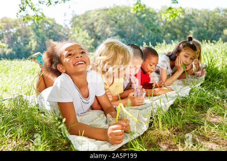 Group of multicultural kids drink water together on a meadow Stock Photo