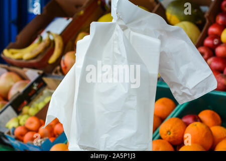 Single use plastic bags hanging outside of the shop next to the fruits and vegetables Stock Photo