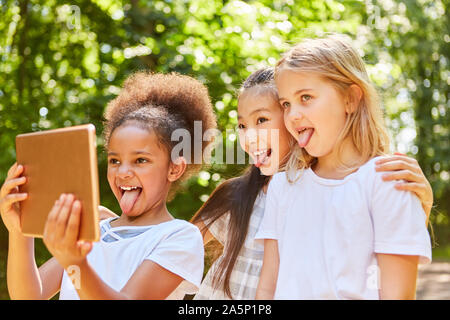 Three girls as girlfriends stick out the tongue while selfie Stock Photo