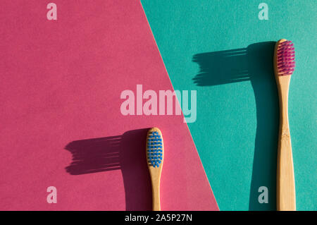 Two wooden bamboo toothbrushes on pink and blue background. Colorful design. Eco trendy concept. Stock Photo