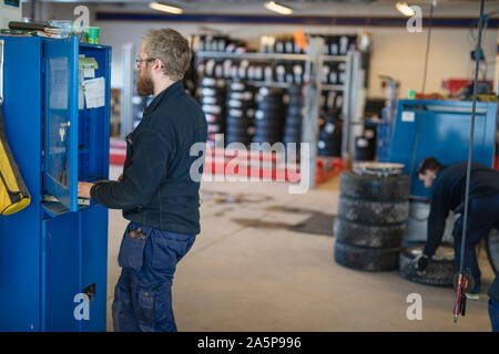 Car mechanic using computer in garage Stock Photo