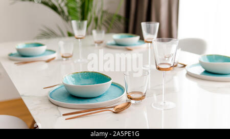 Close-up of served table in a luxury restaurant at the holiday eve. Serving dishes, glass wine glasses and gold cutlery. Concept of catering service. Stock Photo