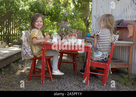 Two girls having tea party in garden Stock Photo