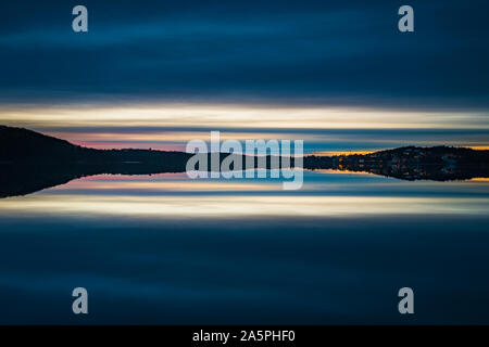 Hills at sunset reflecting in lake Stock Photo