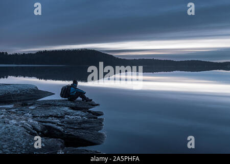 Man looking at sunset over lake Stock Photo