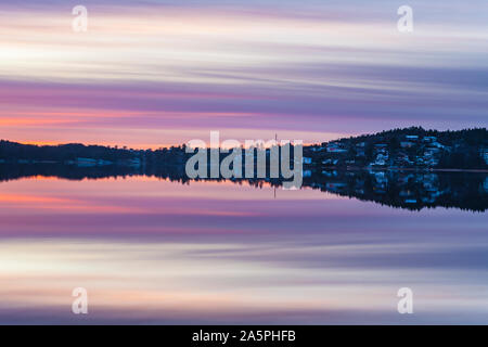 Village at sunset reflecting in lake Stock Photo