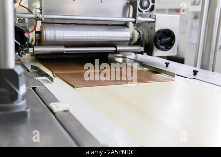 pouring wafer sheets with a thin layer of chocolate on the conveyor of a confectionery factory Stock Photo