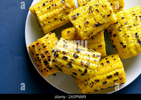 Close up of grilled corn on the cob in plate over blue stone background. Top view Stock Photo
