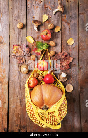 Autumn flat lay with female hand holding turquoise string bag with orange pumpkins.Top view on paper background in on blue mint color. Stock Photo