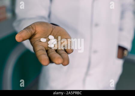 African doctor or pharmacist holding pill, male hand with medication close-up. Man with tablet, concept of pharmacist, drugs, diet pill, antibiotics Stock Photo