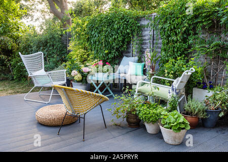 Garden furniture on decking with pot plants Stock Photo